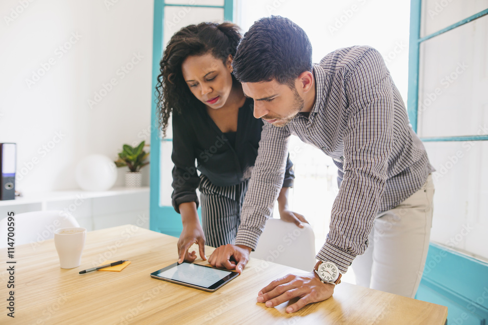 Young businessman and woman looking at digital tablet in office Young businessman and woman looking at digital tablet in office