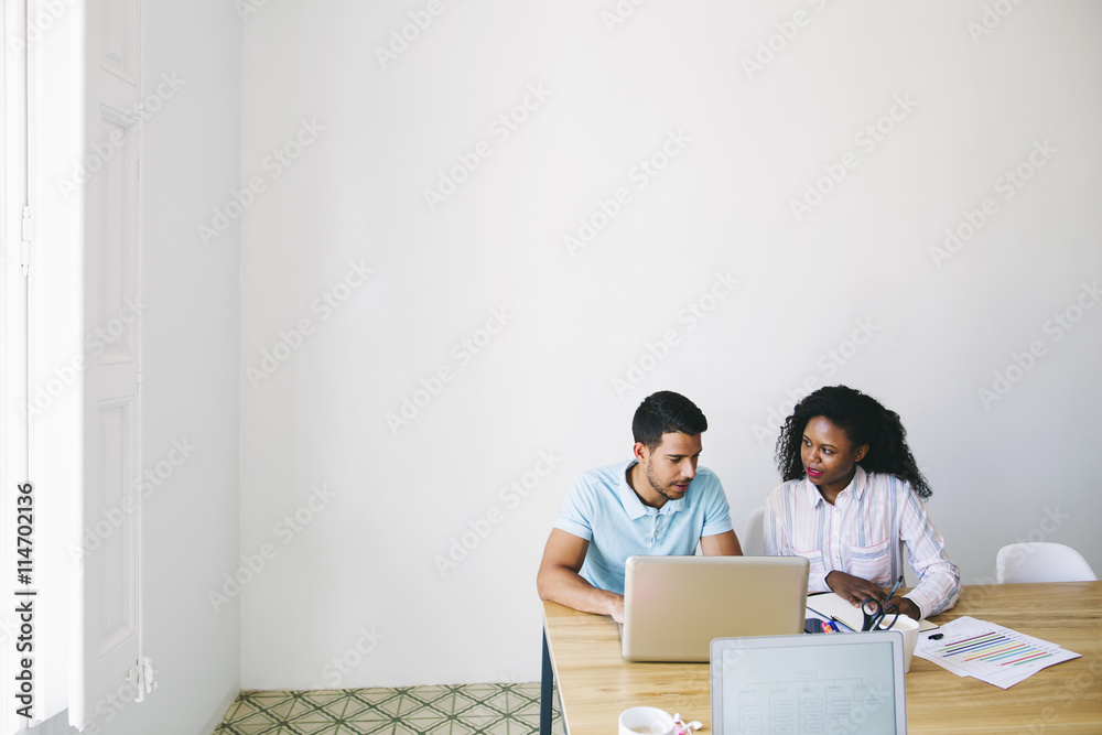 Young businessman and woman working together in office, using laptop Young businessman and woman working together in office, using laptop