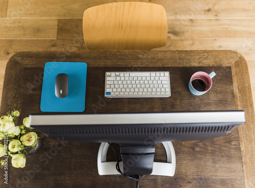 Wooden desk with keyboard, coffee cup and mouse photo