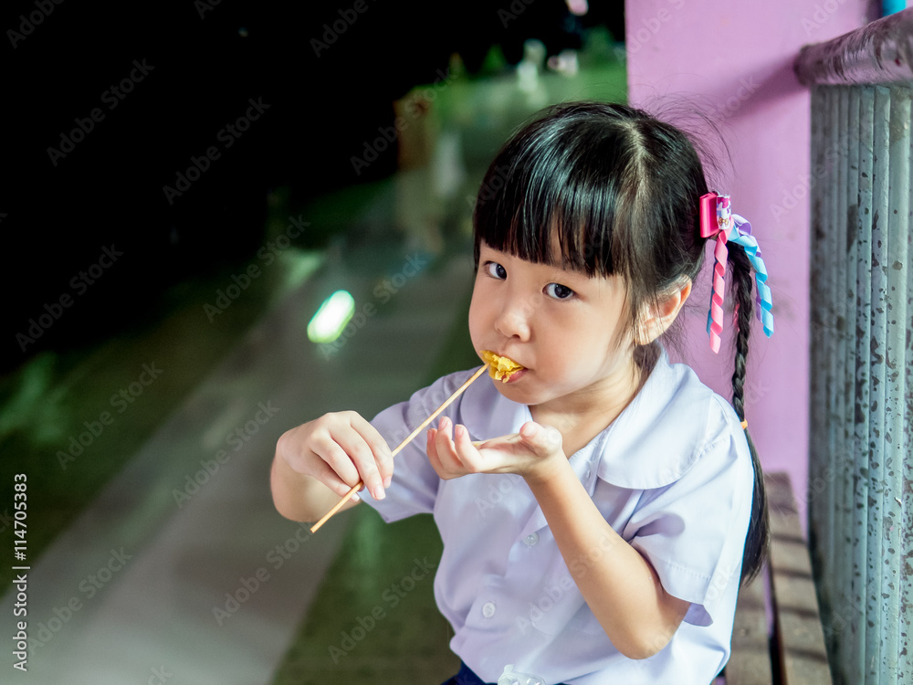 Asian girl child eating a crispy wonton Asian girl child eating a crispy wonton