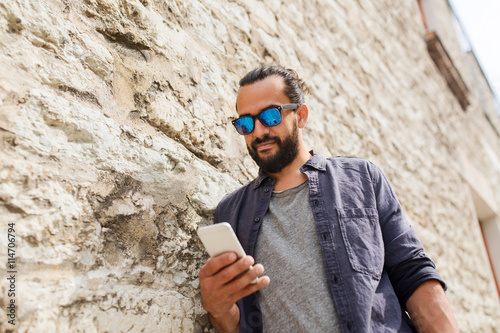 man texting message on smartphone at stone wall