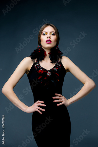 Portrait of beautiful woman with bright makeup red lips and feather earings