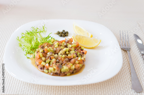 Vegan salad with lemon on white plate in restaurant.