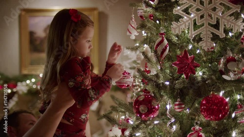 Medium panning shot of father and daughter decorating Christmas tree / Cedar Hills, Utah, United States