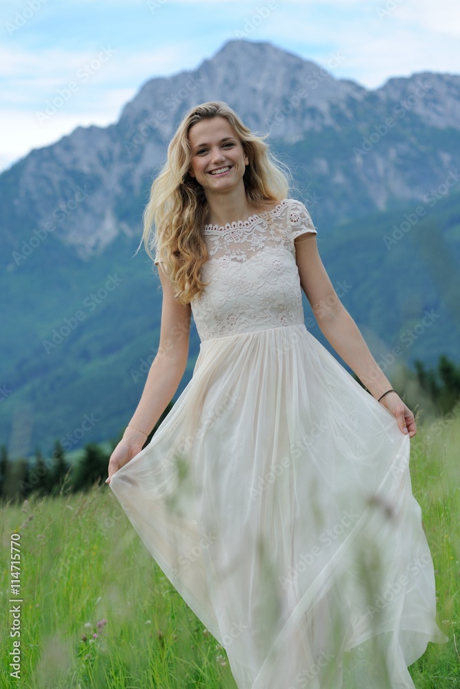 Junge Frau läuft in einem langen Kleid über eine Bergwiese im Berchtesgadener Land Junge Frau läuft in einem langen Kleid über eine Bergwiese im Berchtesgadener Land