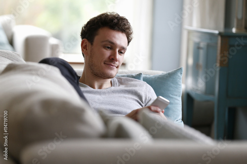 Εκτύπωση καμβά Man Relaxing On Sofa Checking Mobile Phone