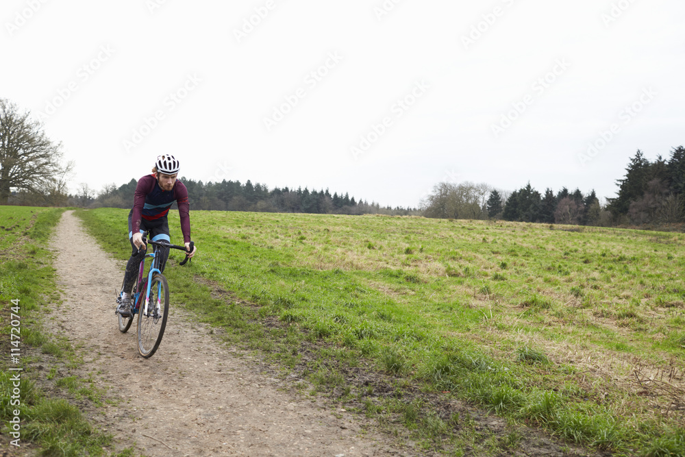 Cross-country cyclist riding down a path in open countryside