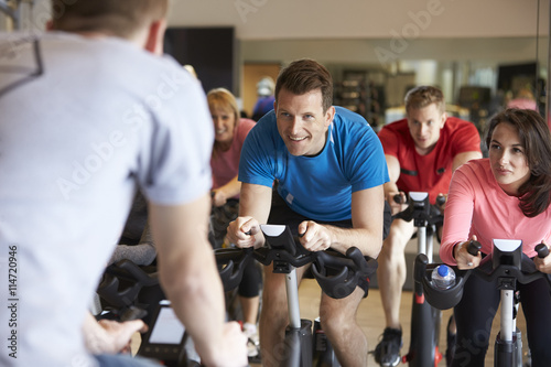 Instructor in foreground with spinning class at a gym photo