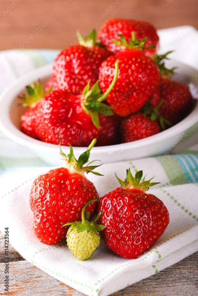 Red and green strawberries on towel in front of bowl Red and green strawberries on towel in front of bowl