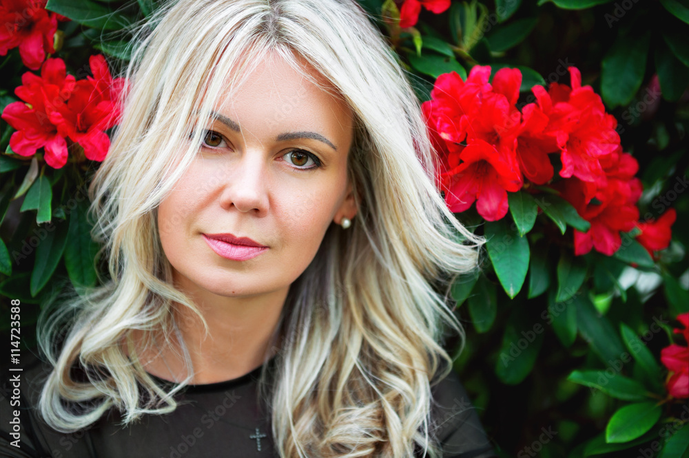 Beautiful blond woman with red flowers on background Beautiful blond woman with red flowers on background