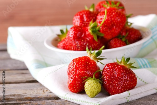 Red and green strawberries on cloth in front of bowl