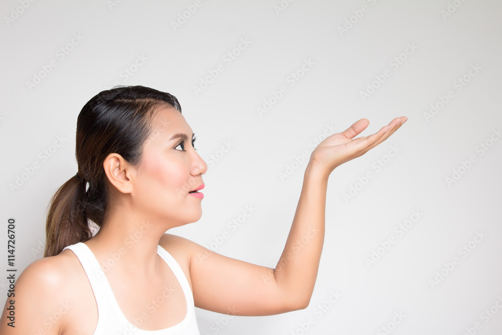 Smiling young woman is pointing at copy space over white backgro Smiling young woman is pointing at copy space over white backgro
