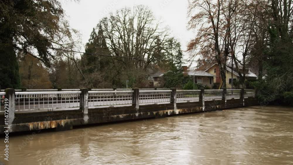 Flooding stream almost touching the bottom of a bridge in a suburban neighborhood Flooding stream almost touching the bottom of a bridge in a suburban neighborhood