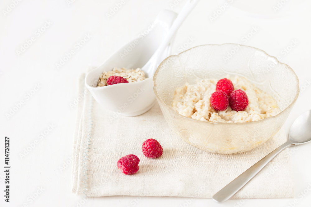 Oatmeal porridge with raspberries on bright wooden table