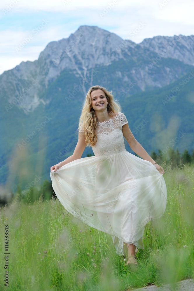 Junge Frau im langen Sommerkleid auf einer Bergwiese vor dem Hochstaufen im Berchtesgadener Land