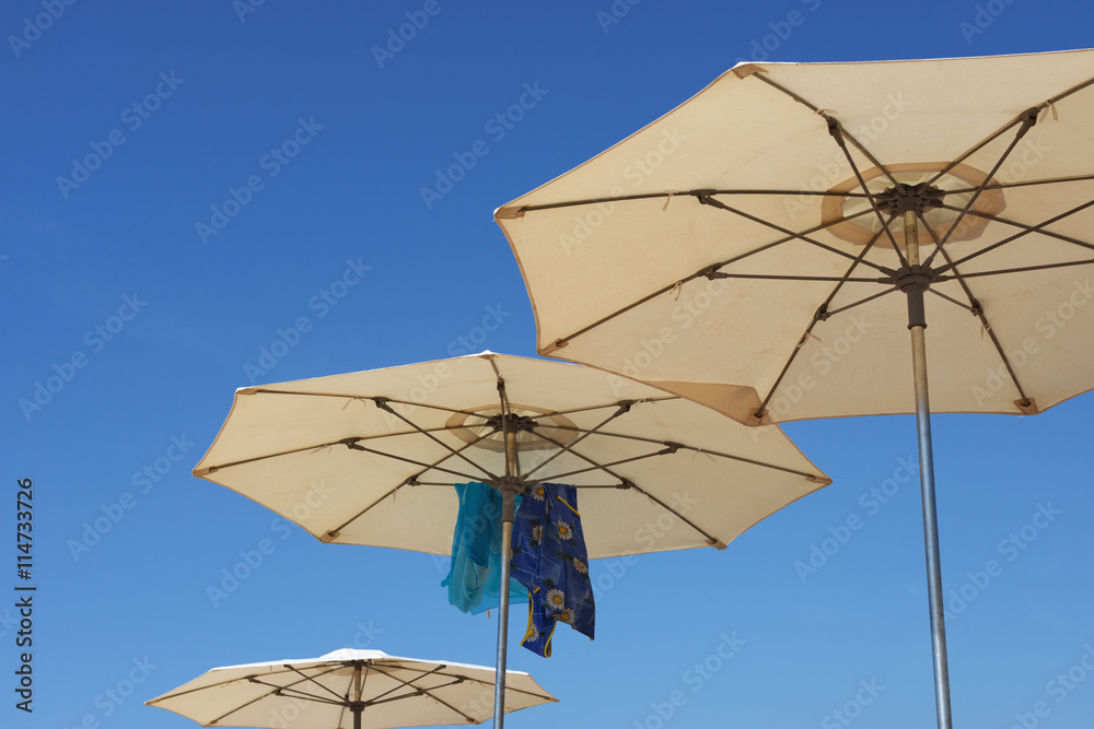 Beach parasols are on bright blue sky background. Beach parasols are on bright blue sky background.