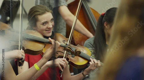 Medium shot of teenage girls playing violins in orchestra practice / American Fork, Utah, United States