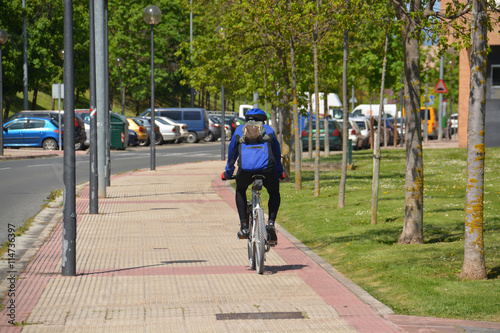 ciclista circulando por la acera de una calle