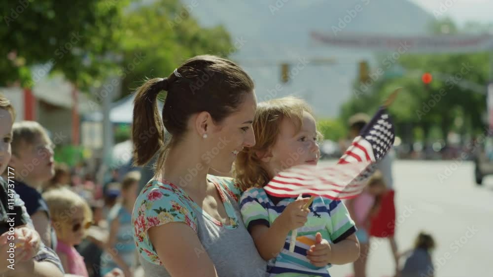 Medium slow motion shot of family watching parade / American Fork, Utah, United States