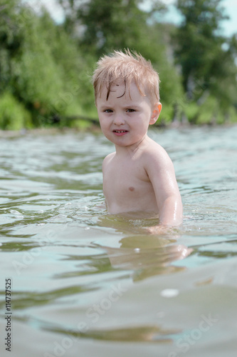 Boy swims in the lake in the summer