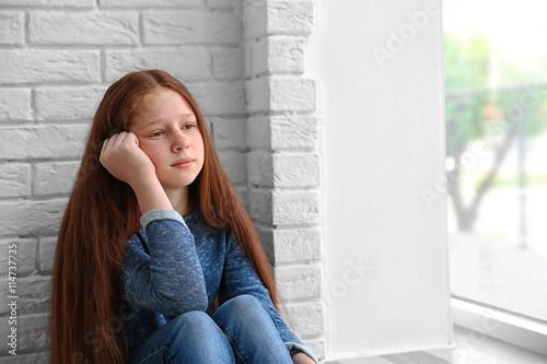 Sad girl sitting near window