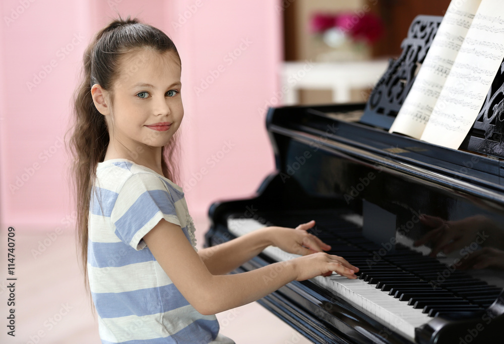 Fototapeta Small girl playing piano