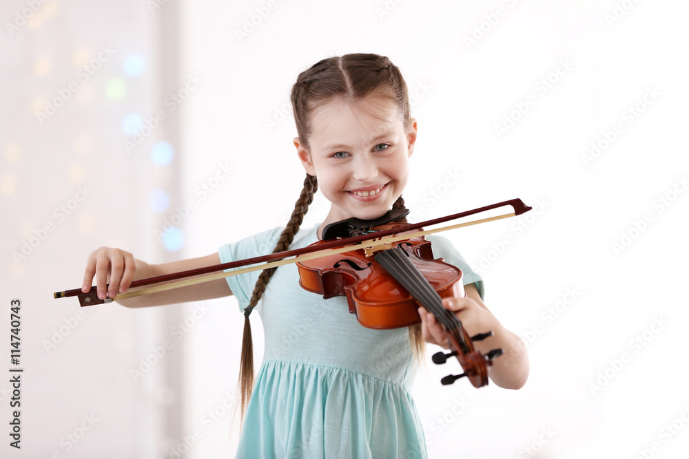 Little girl playing violin on light background Little girl playing violin on light background