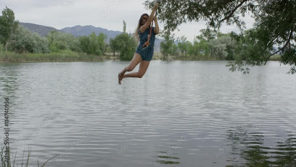 Wide slow motion panning shot of woman swinging into lake / Mona, Utah, United States Wide slow motion panning shot of woman swinging into lake / Mona, Utah, United States