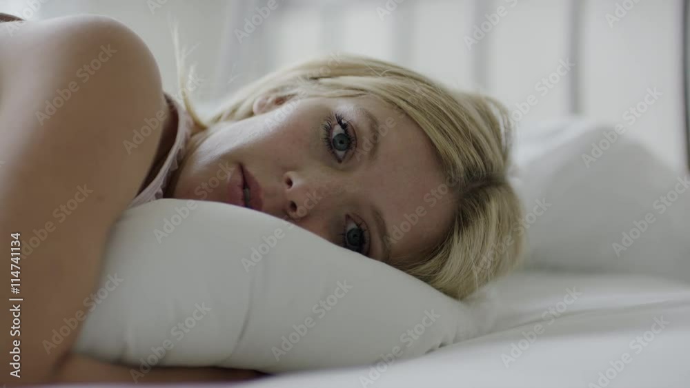 Close up slow motion shot of woman hugging pillow on bed / Cedar Hills, Utah, United States Close up slow motion shot of woman hugging pillow on bed / Cedar Hills, Utah, United States