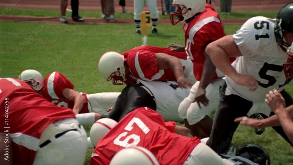 Opposing football players crashing into each other and falling down
