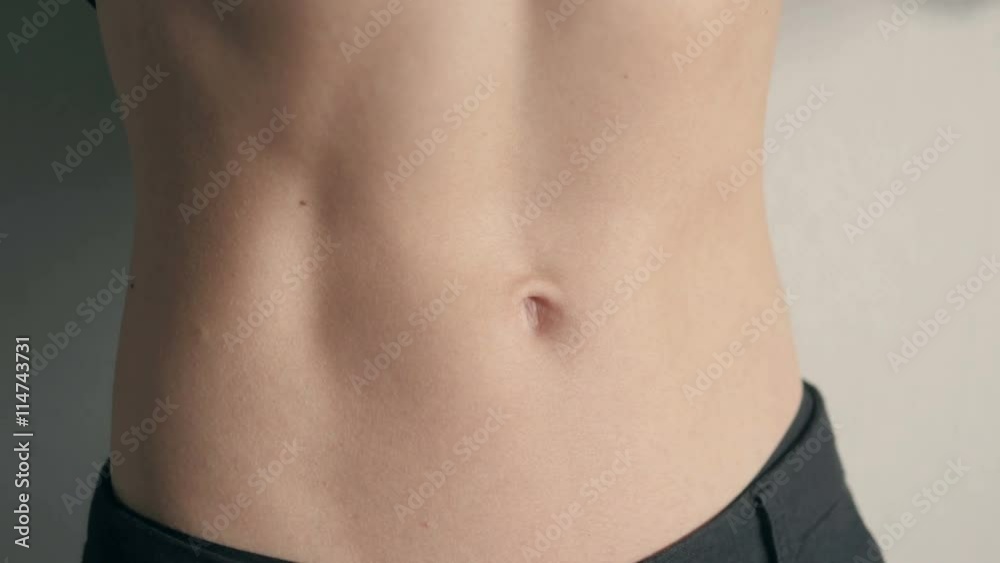 Close-up of the abdominal muscles young athlete on gray background Close-up of the abdominal muscles young athlete on gray background