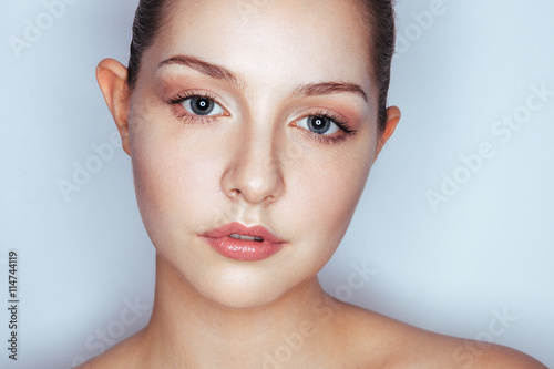 Glamour close up portrait of young beautiful woman model with trendy makeup. Fashion shiny highlighter on skin, sexy gloss lips make-up and dark eyebrows.