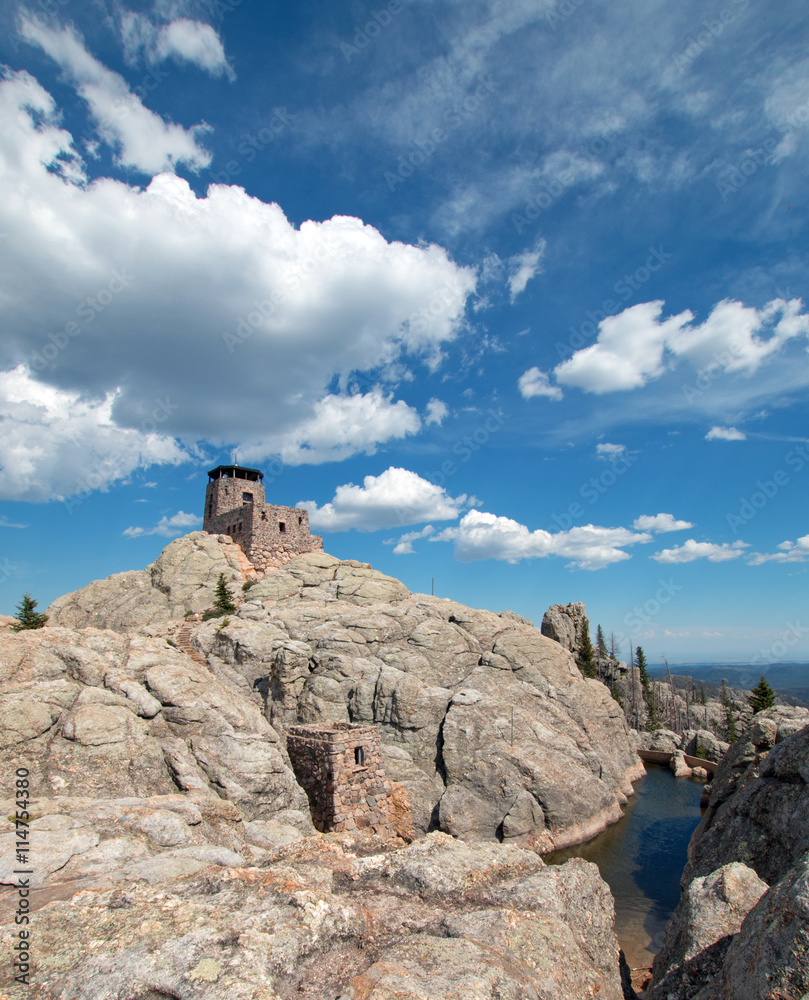 Harney Peak Fire Lookout Tower and pump house with small dam under summer blue sky in Custer State Park in the Black Hills of South Dakota USA