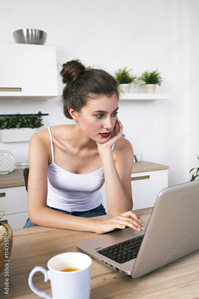Portrait of beautiful brunette using laptop in kitchen Portrait of beautiful brunette using laptop in kitchen