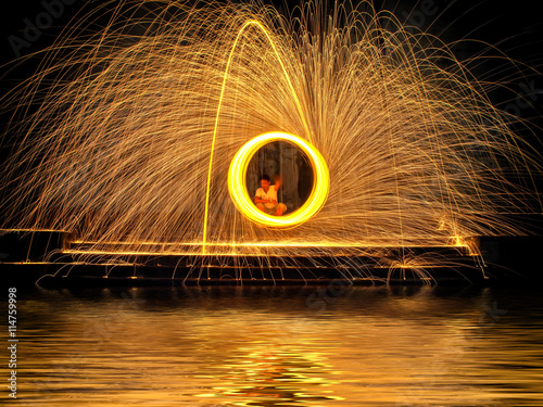 Hot Golden Sparks Flying from Man Spinning Burning Steel Wool on the Stair near River with Water Reflection., Long Exposure Photography using Steel Wool Burning.