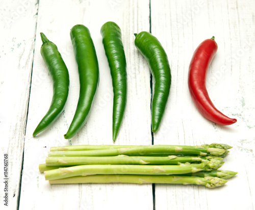 Green and red peppers and asparagus on a wooden background