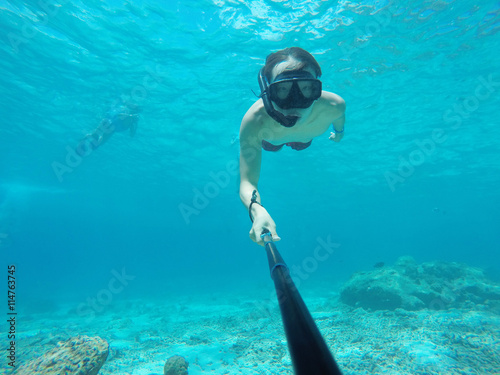 Underwater selfie shot with selfie stick. Deep blue sea. Wide angle shot.