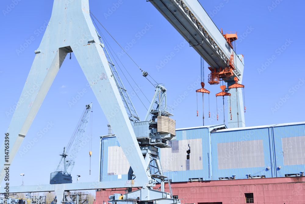Obraz premium Wharf or shipyard of Hamburg Harbor, Germany. Harbor cranes and production halls at a commercial dock. Industry buildings.