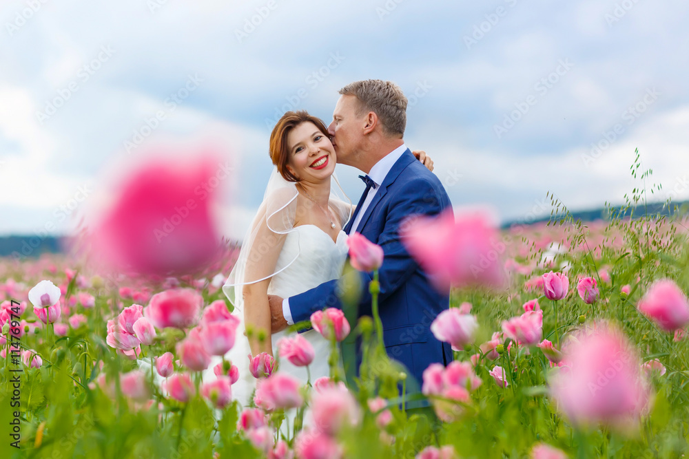 Happy wedding couple in pink poppy field