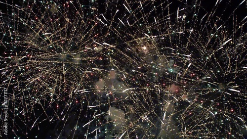 An aerial fireworks display of layered bursts followed by rockets shooting up from below