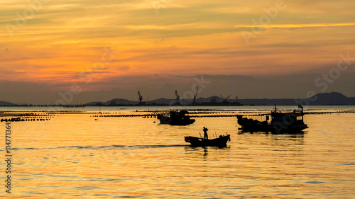 Silhouette of small fisherman boat in sea with sunset sky