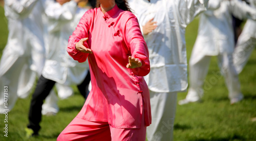 Woman with pink silk dress perform the exercises in the park