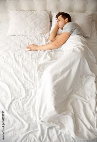 Young man sleeping alone in...
