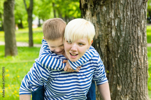  Young modern mom and her son in the same striped shirts in the park on a sunny summer day