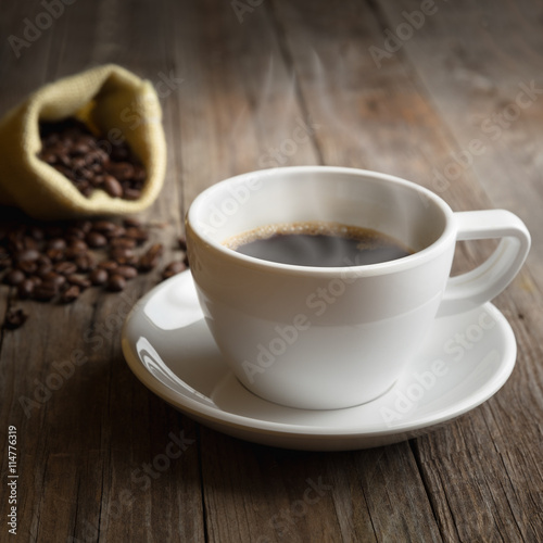 Closeup coffee cup and beans on wooden table