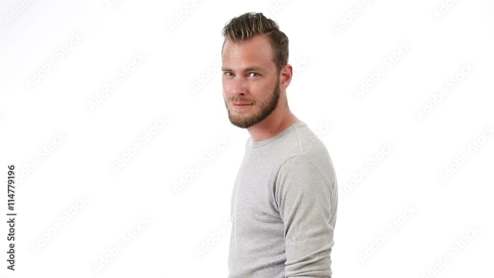 Fashionable man wearing a grey shirt walking in front of a white background looking at camera. Smiling. Fashionable man wearing a grey shirt walking in front of a white background looking at camera. Smiling.