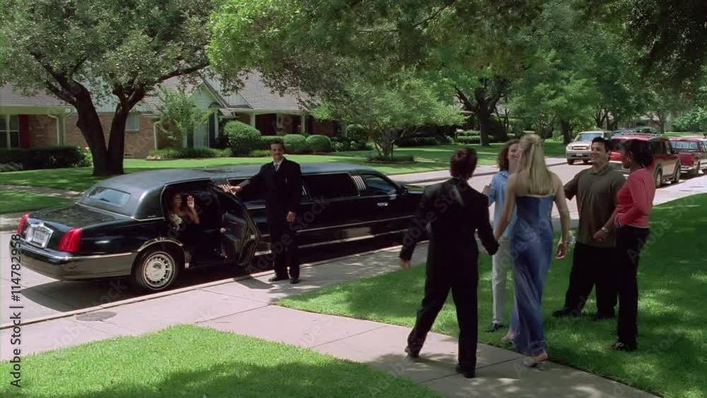 Stretch limo waiting for prom-bound teenage couple as parents say good-bye
