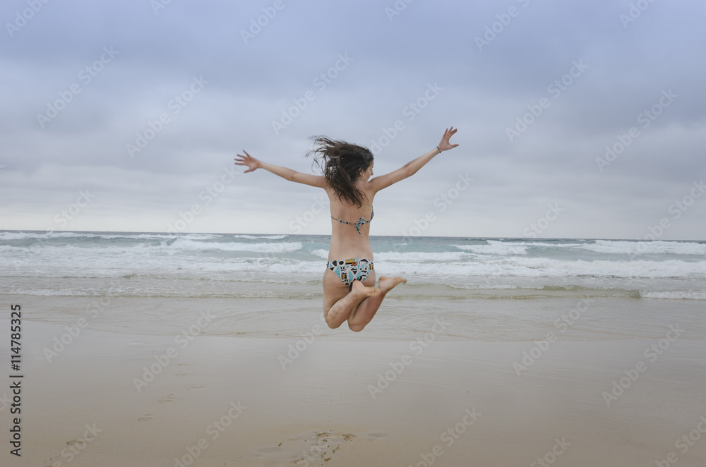 Woman with bikini jumping in the air on beach Woman with bikini jumping in the air on beach