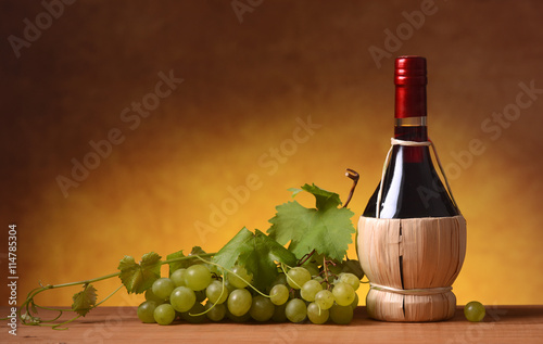 fiasco di vino rosso con grappolo di uva