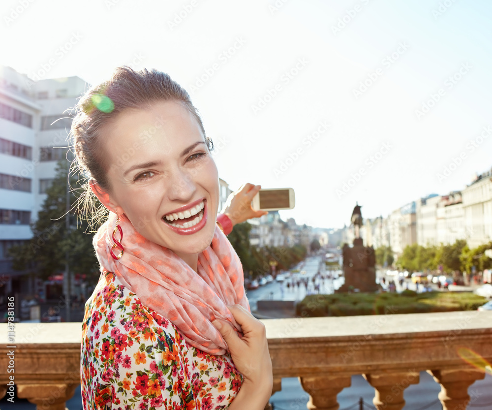 Fototapeta premium Portrait of happy woman taking photos with cellphone in Prague